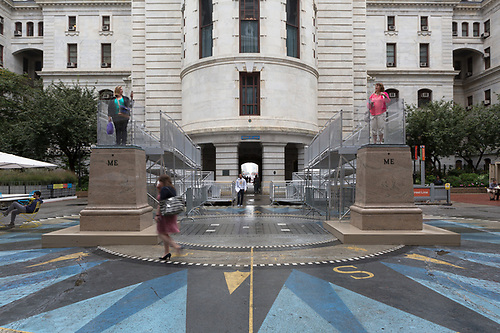 Photograph of two people standing atop pedestals outside of City Hall in Philadelphia