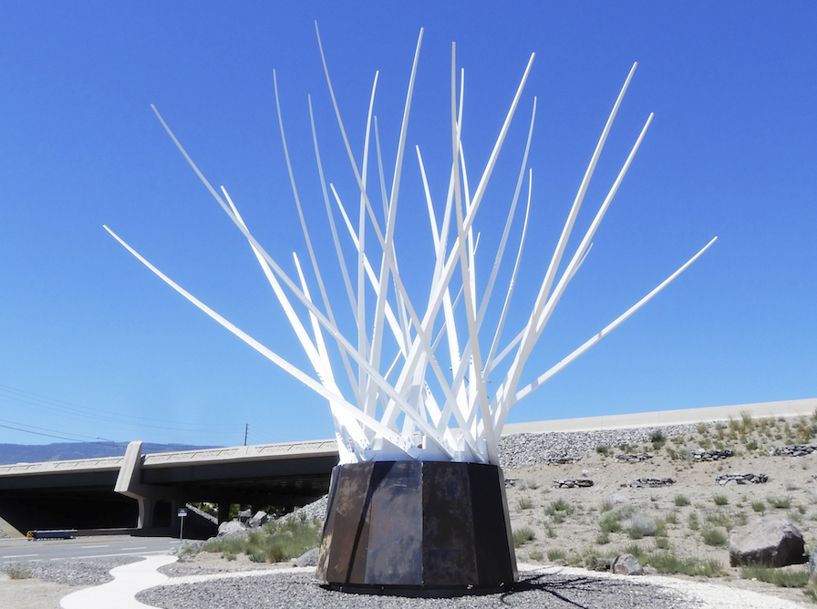 A white sculpture placed outside in the desert.