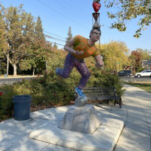 A sculpture depicting a man balancing various colorful items on his head