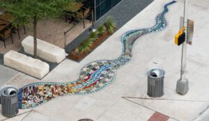 Aerial view of a colorful mosaic pathway embedded in a sidewalk, resembling a river.