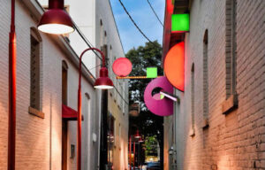 Narrow alleyway with colorful geometric decorations and red street lamps.