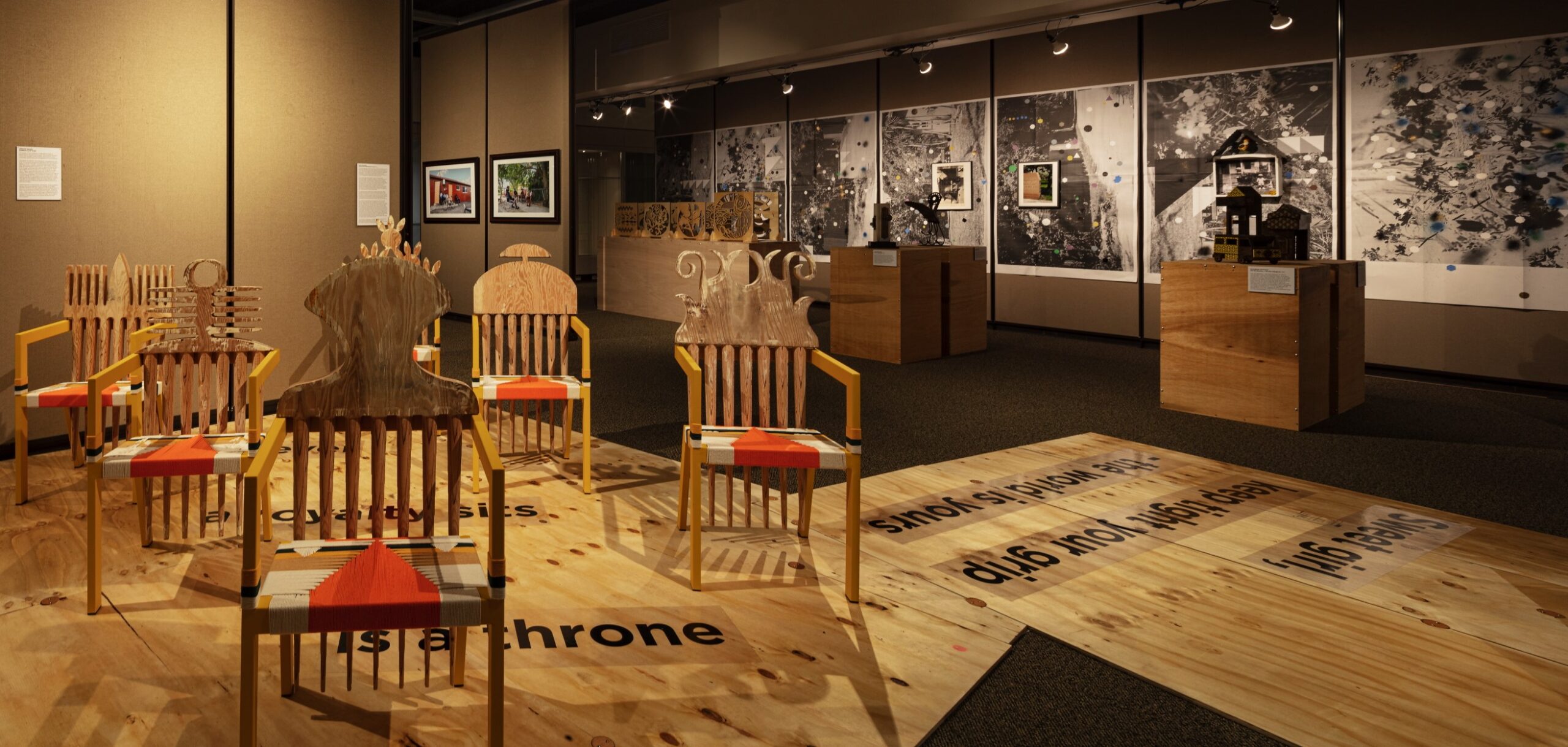 Image of exhibition featuring a series of chairs placed in the middle of installation surrounded by photographs on the wall