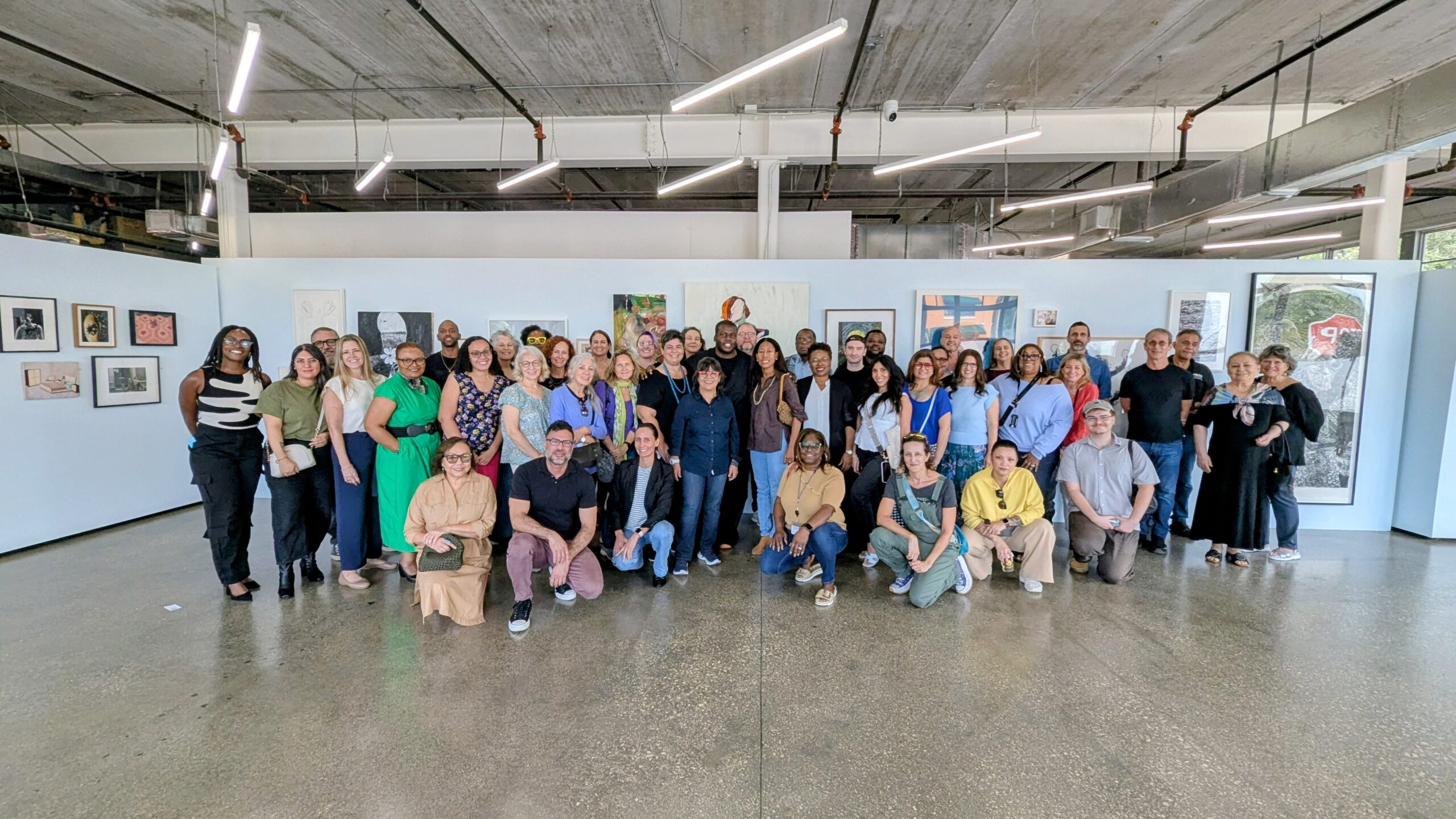 Group photo of about 50 people in a gallery space